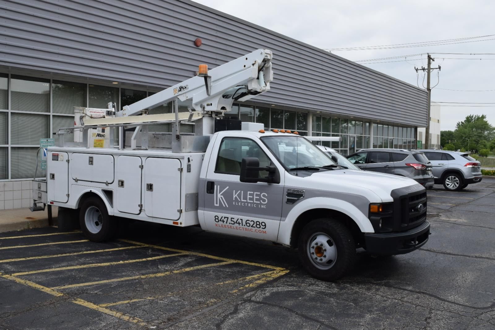 A white utility truck is parked in a parking lot in front of a building.