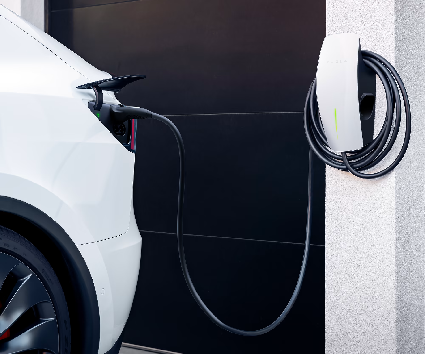 A white tesla model y is being charged at a charging station.