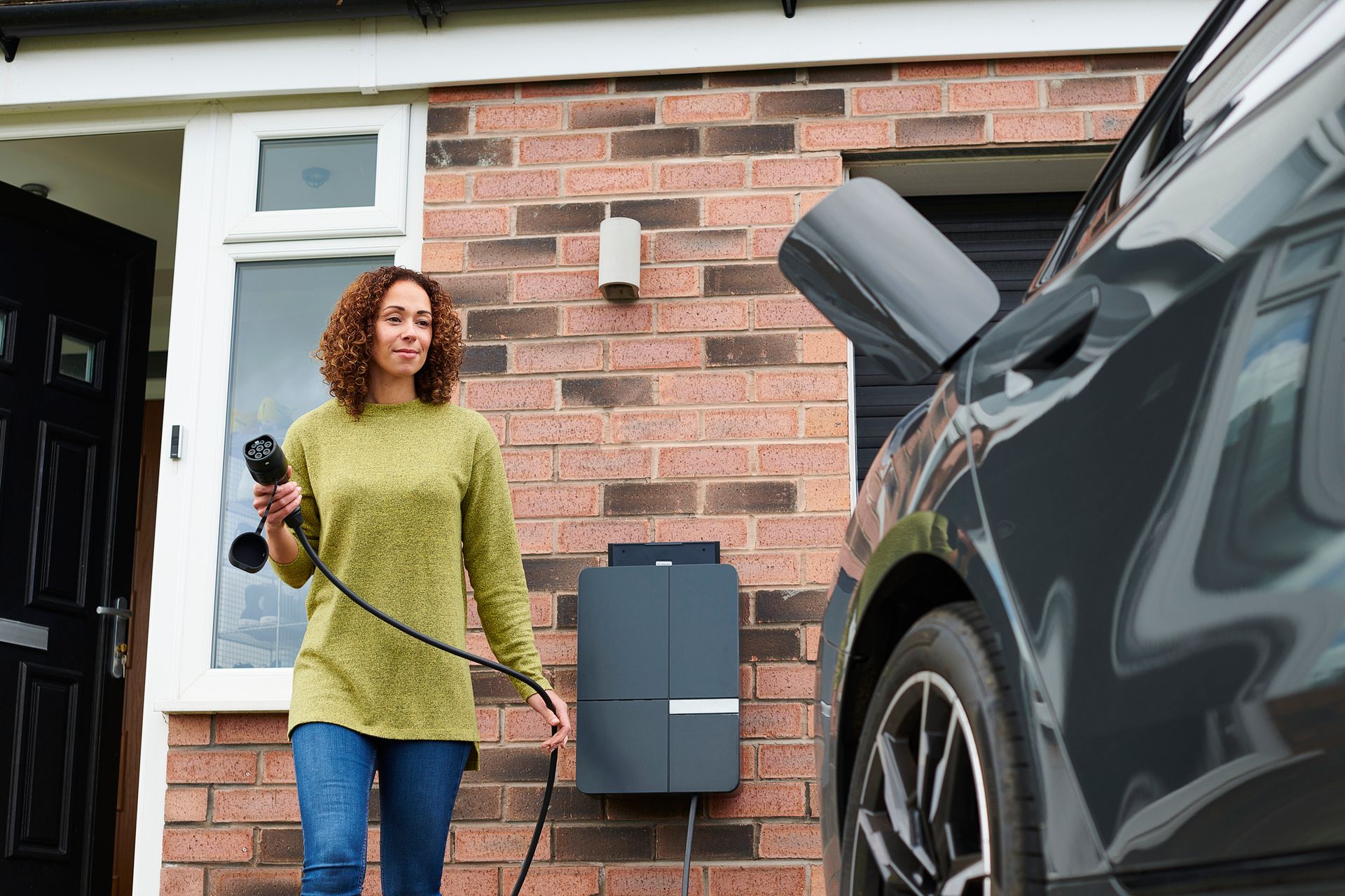 Homeowner charging electric car on driveway by Klees Electric.