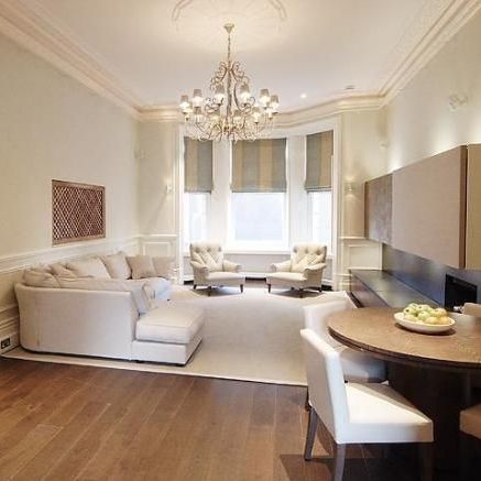 Living room with chandelier, seating, dining table, and a bay window.
