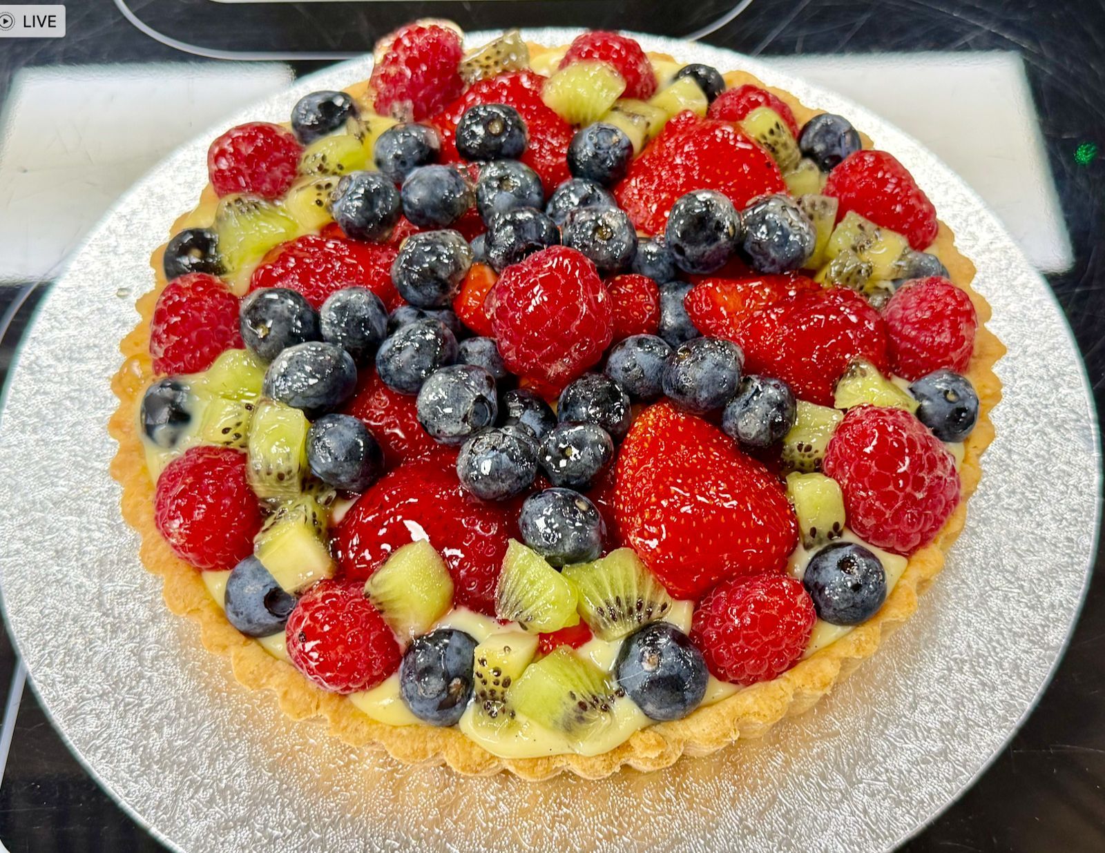 Fruit tart with strawberries, blueberries, raspberries, and kiwi on a golden crust.