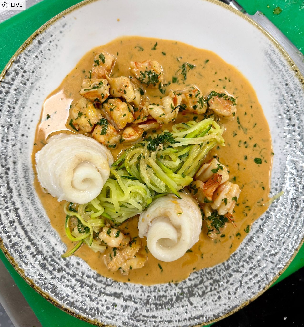 Plate of food with shrimp, fish, zucchini noodles, and orange sauce.