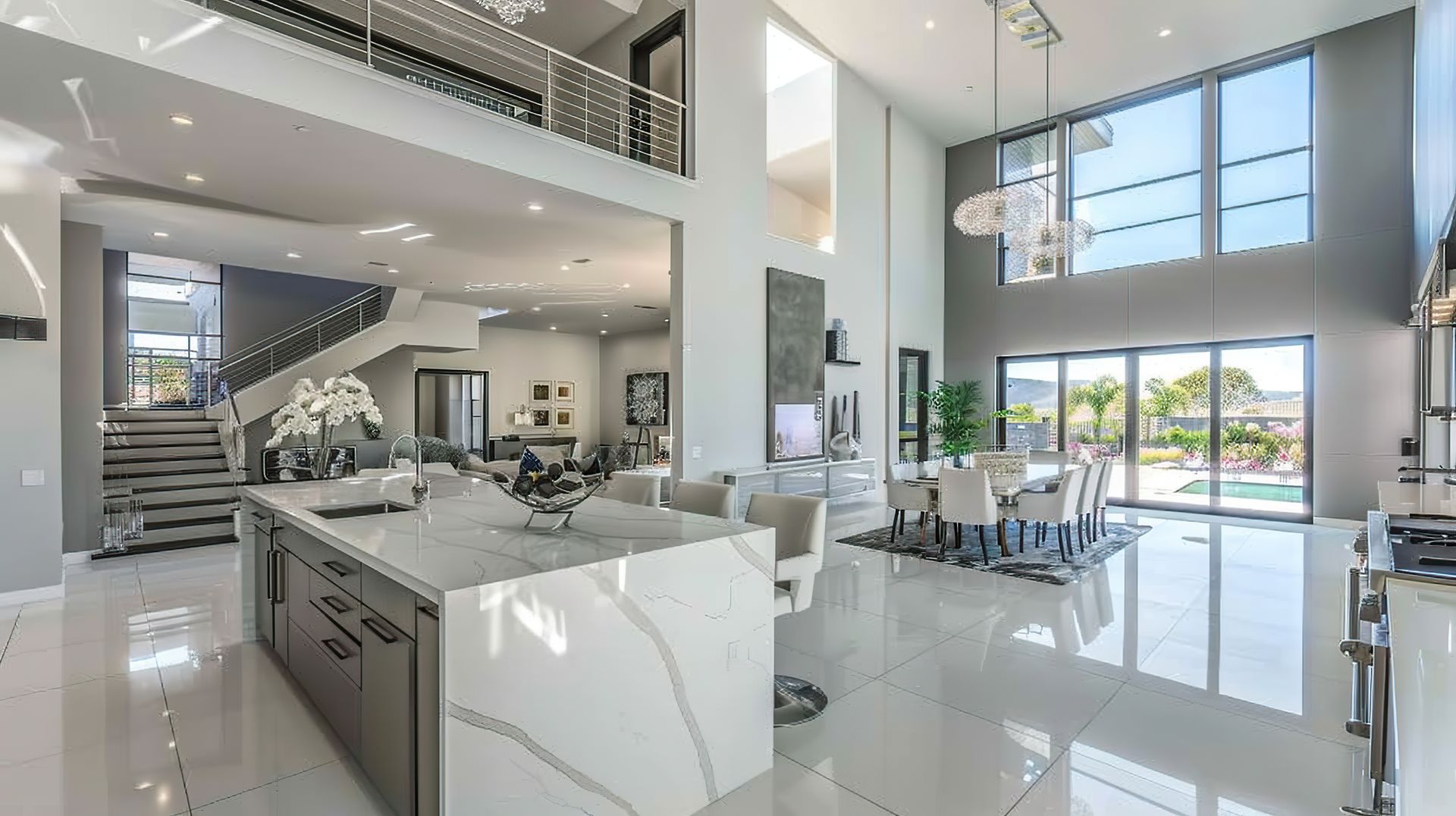 Modern luxury kitchen and open living area with white glossy floors, high ceilings, and large windows.