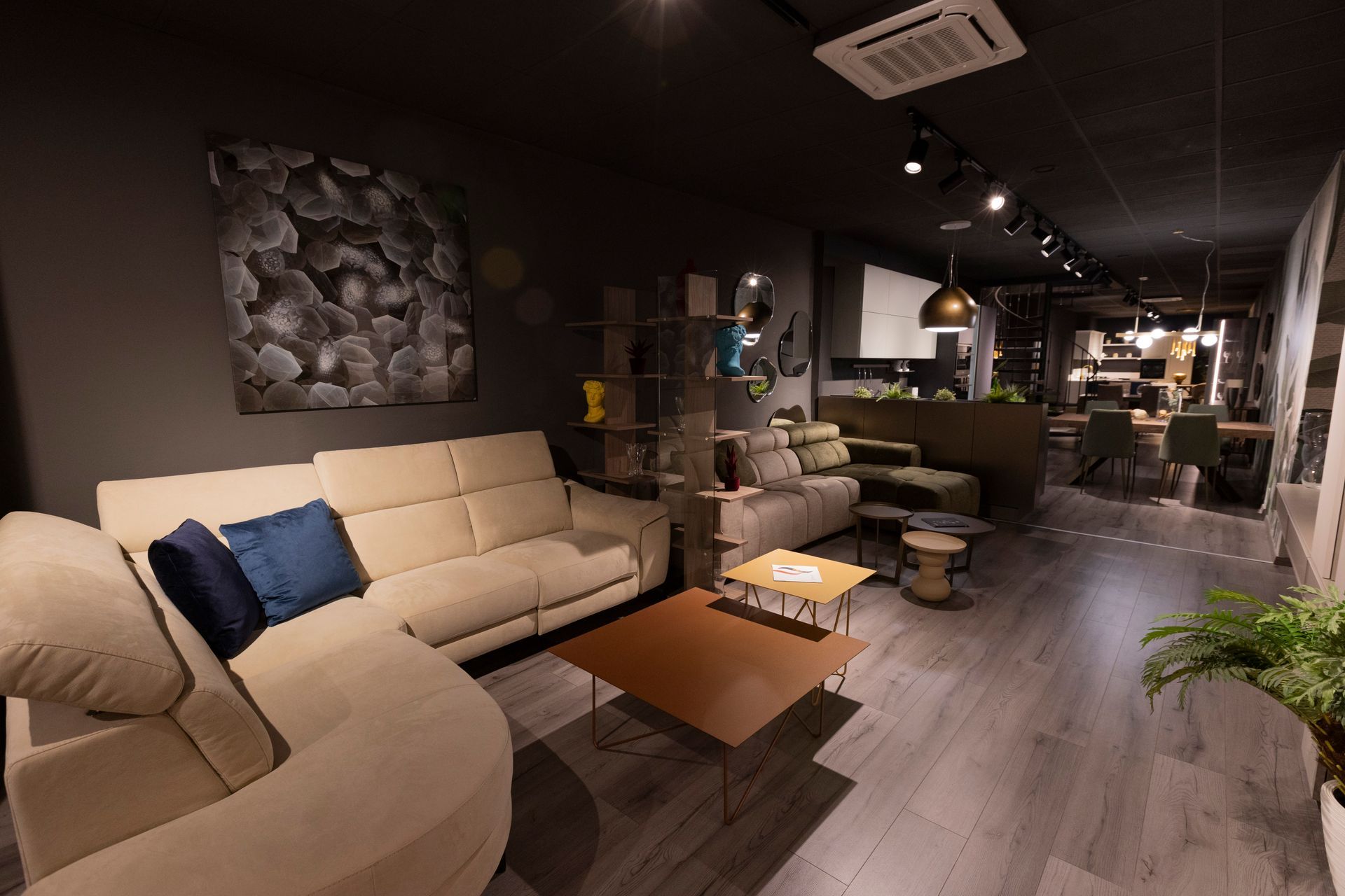 Soggiorno con divano componibile beige, tavolino da caffè e quadri decorativi alle pareti.