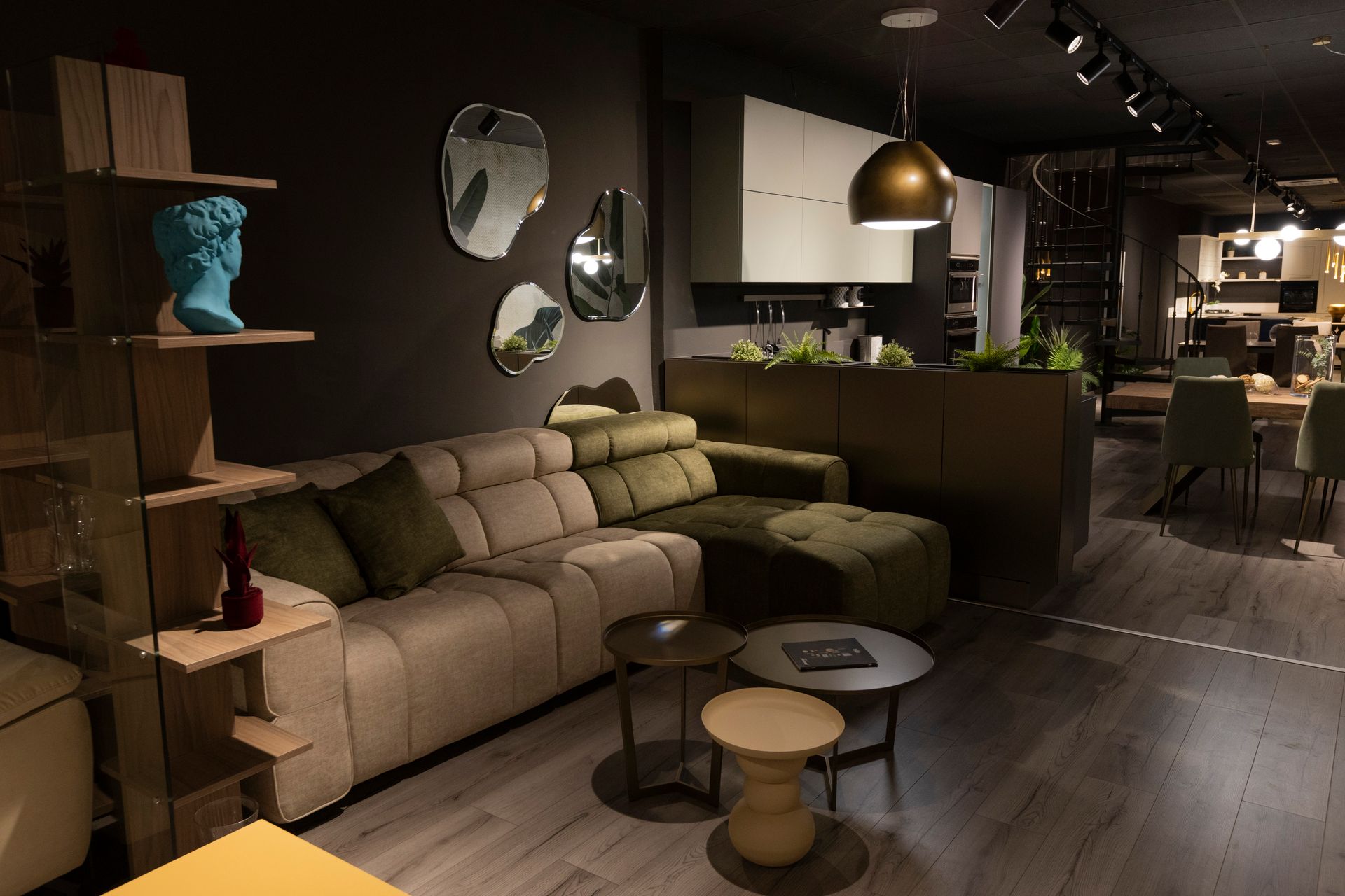 Soggiorno moderno con divano componibile verde oliva, tavolini e mensole decorative.