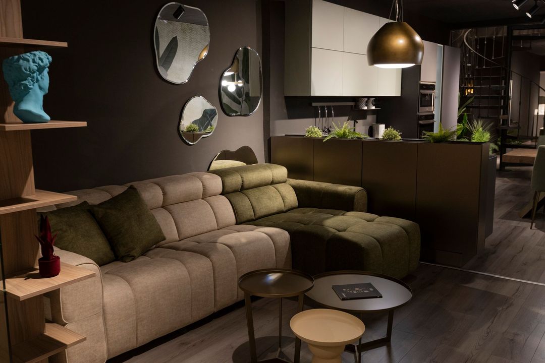 Soggiorno con divano componibile, specchi decorativi e tavolini da caffè.