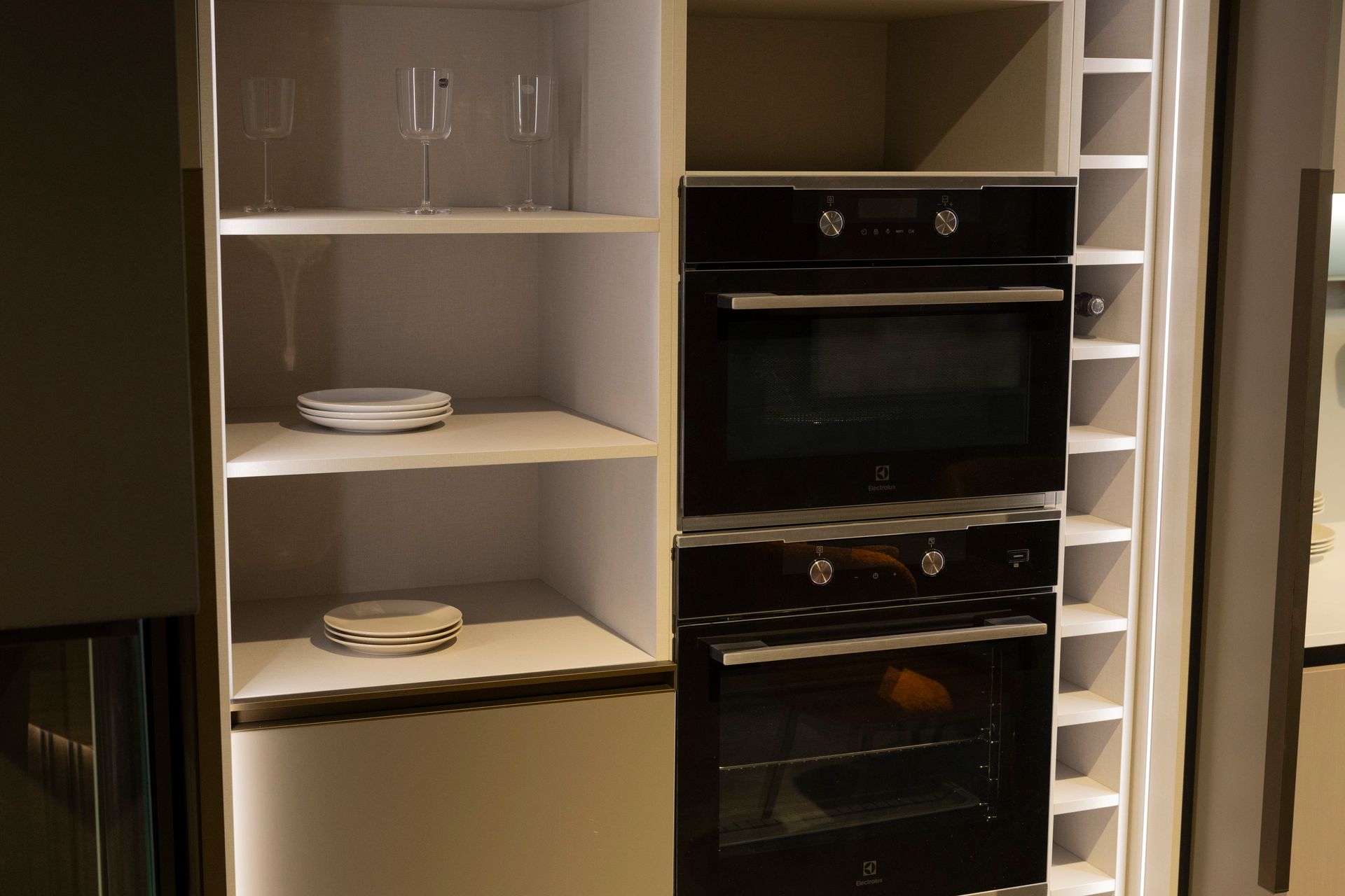 Mobile da cucina integrato con forni, ripiani per piatti e bicchieri e portabottiglie.