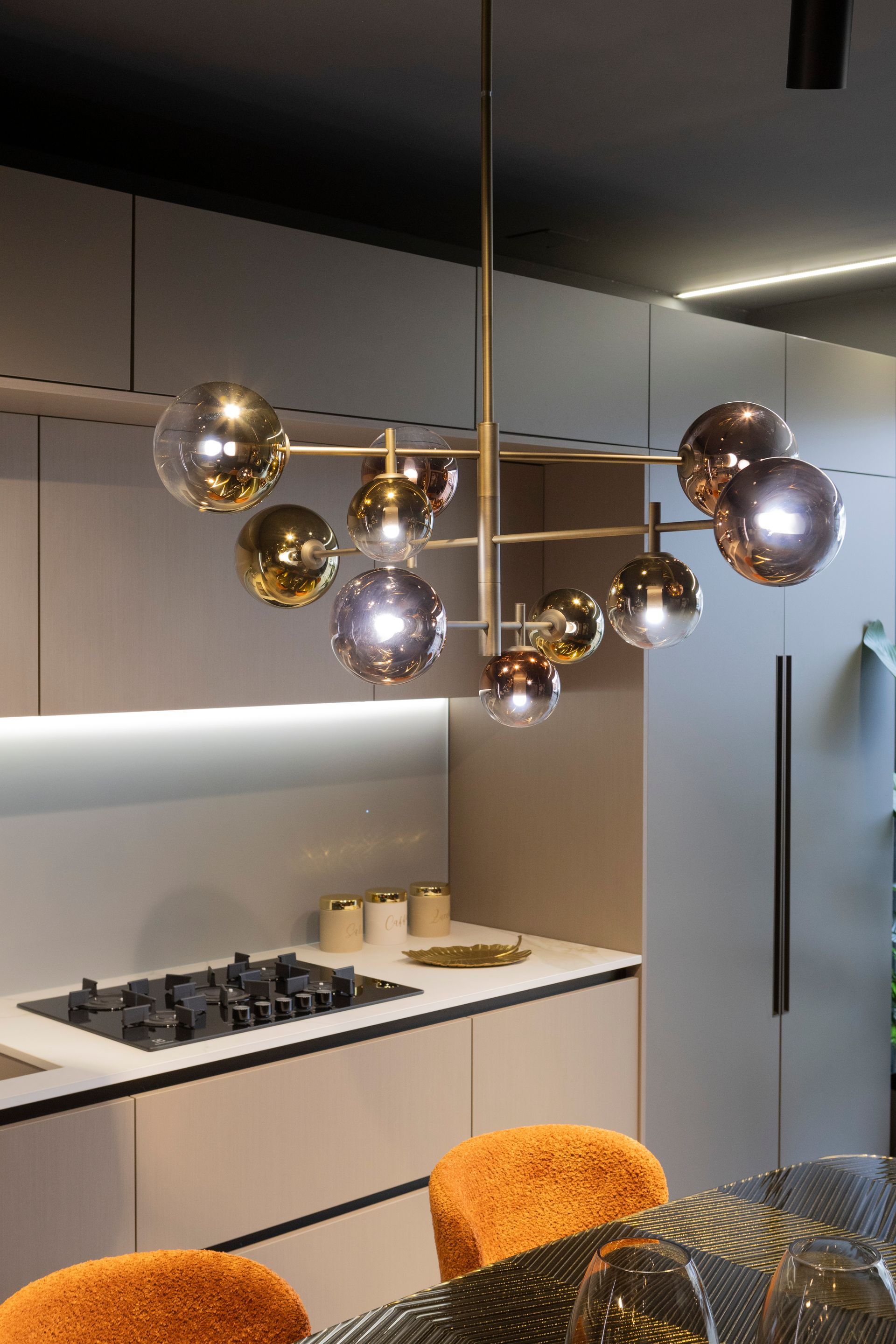 Cucina moderna con lampadario dorato con lampadine sferiche in vetro.