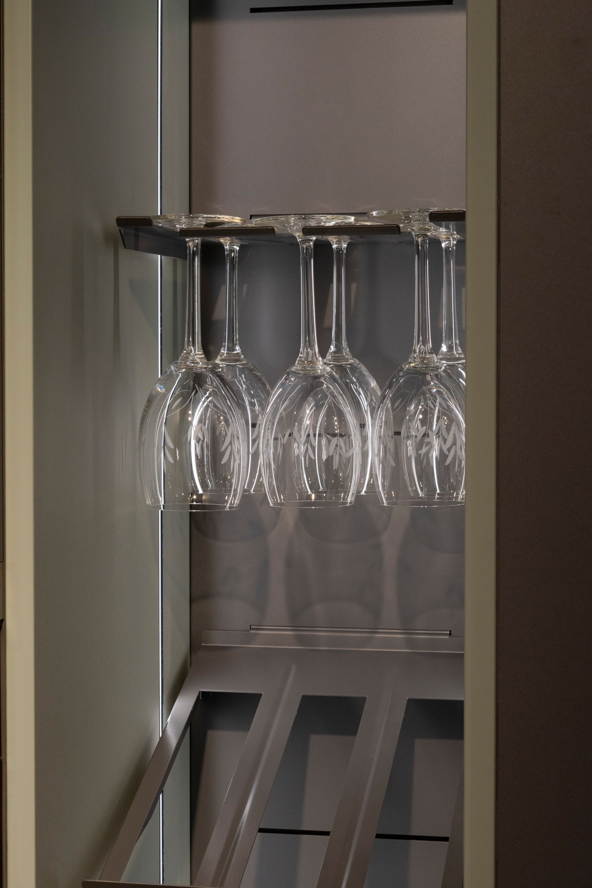 Bicchieri da vino appesi a testa in giù in un mobiletto incorporato con rastrelliera.