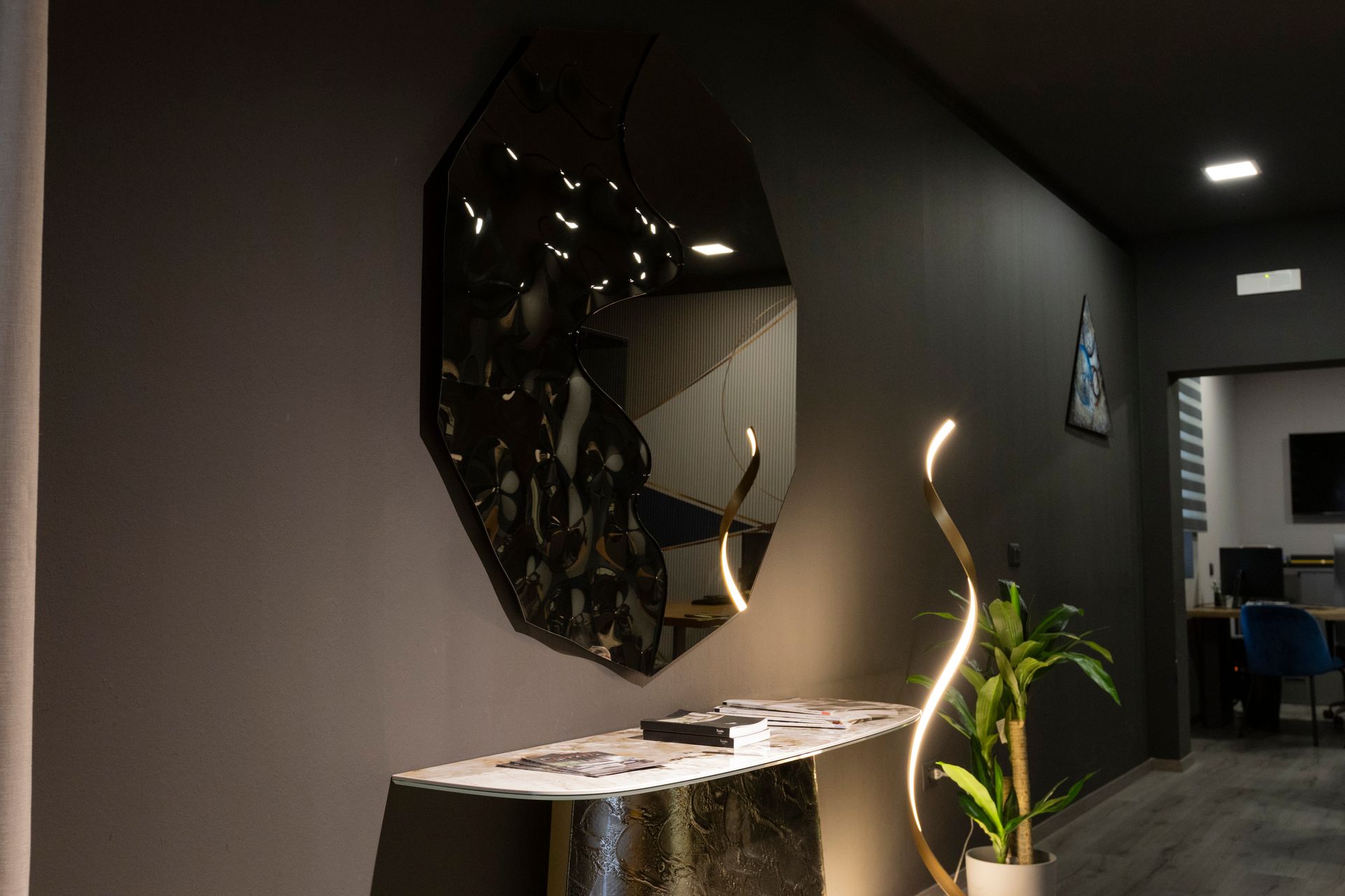 Specchio geometrico nero sopra una consolle in marmo con luce decorativa.