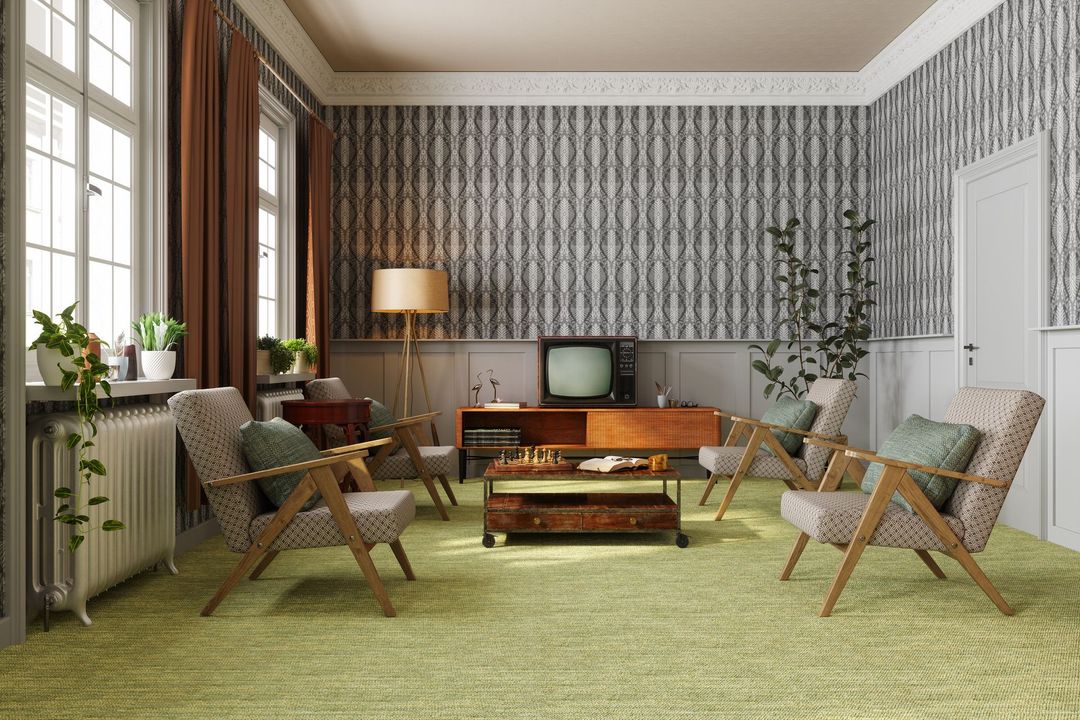 Soggiorno retrò con carta da parati a motivi, mobili in legno e tappeto verde.