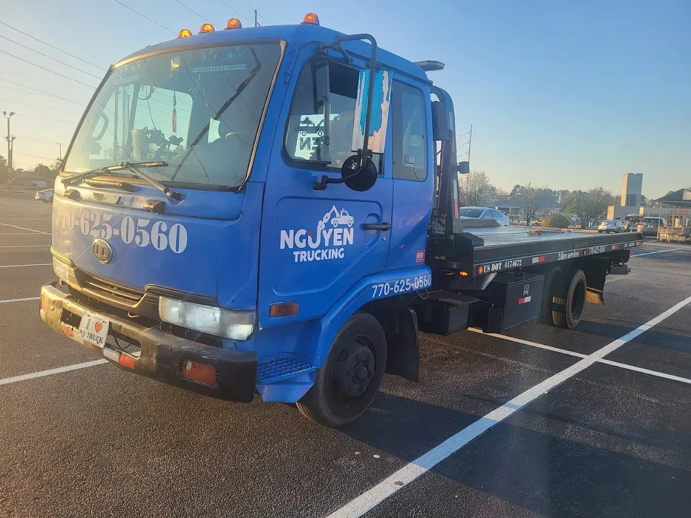 Blue tow truck in a parking lot with a