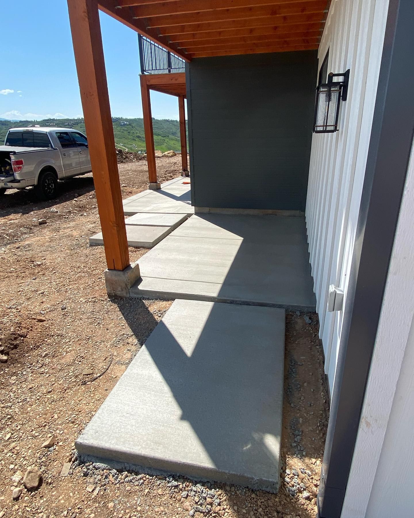 A white truck is parked on the side of a building next to a concrete walkway.