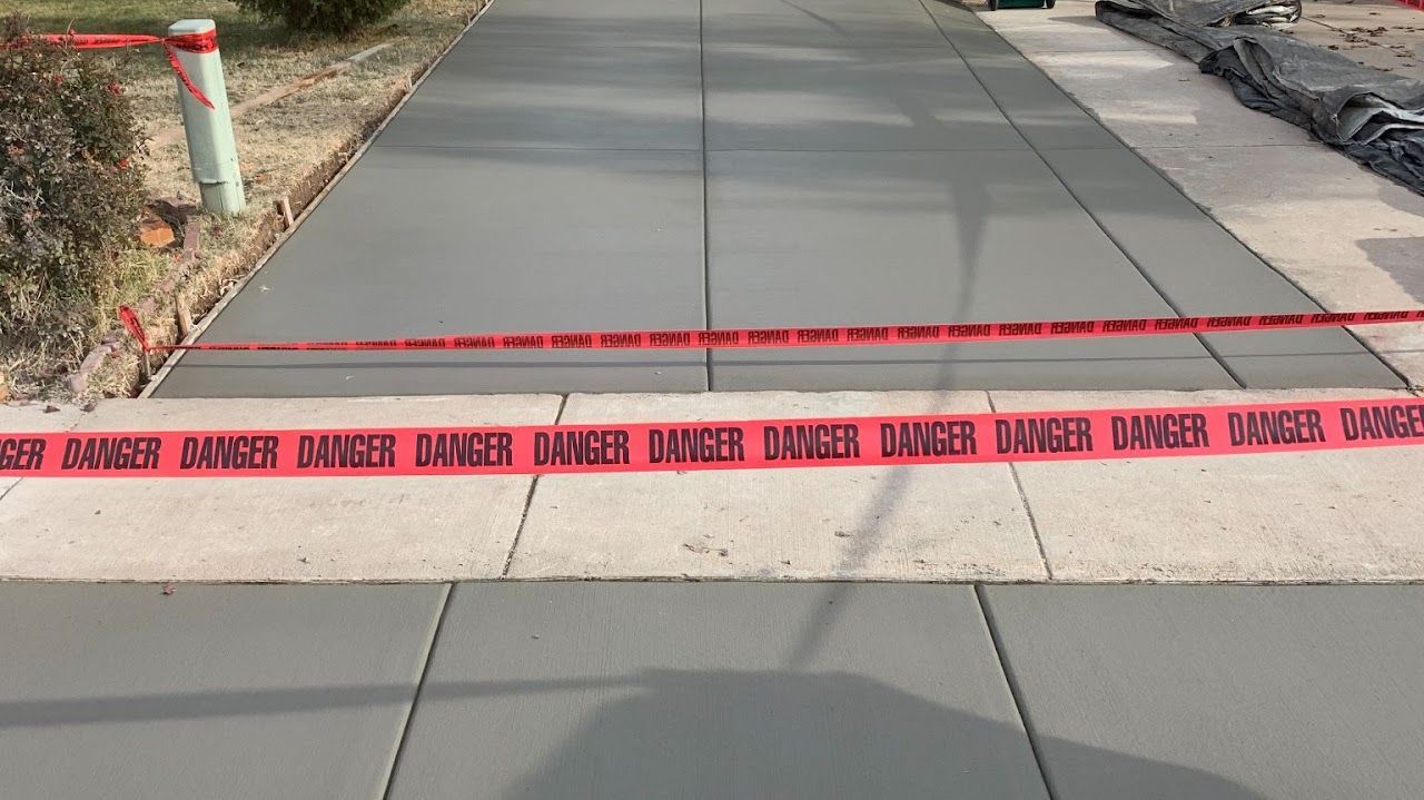 A concrete sidewalk with a red tape that says danger on it.