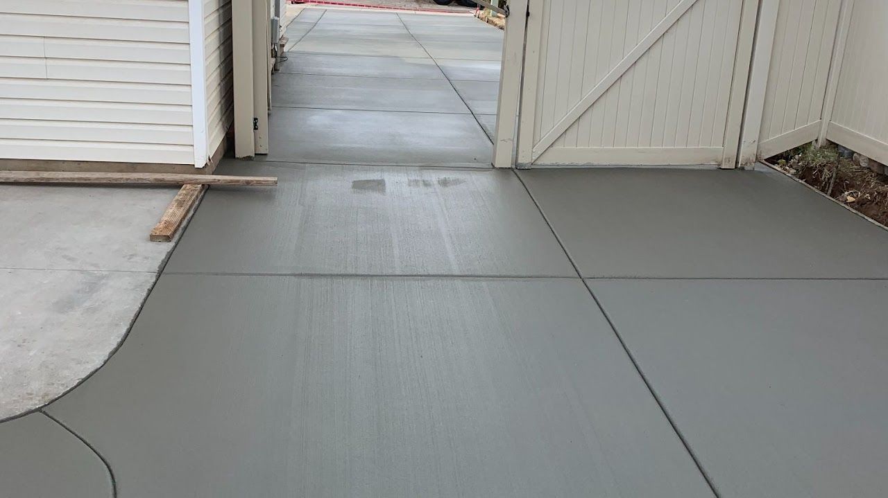 A concrete walkway is being built next to a white gate.