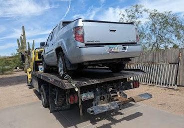 A silver truck is sitting on top of a tow truck. A silver truck is sitting on top of a tow truck.