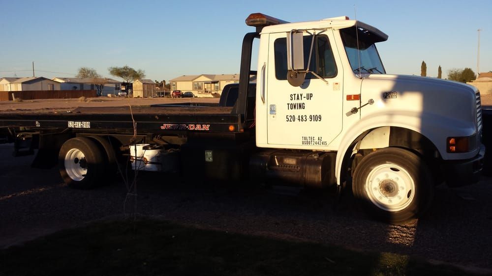 A white tow truck is parked on the side of the road A white tow truck is parked on the side of the road