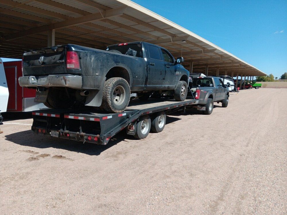 A truck is being towed on a trailer in a parking lot A truck is being towed on a trailer in a parking lot