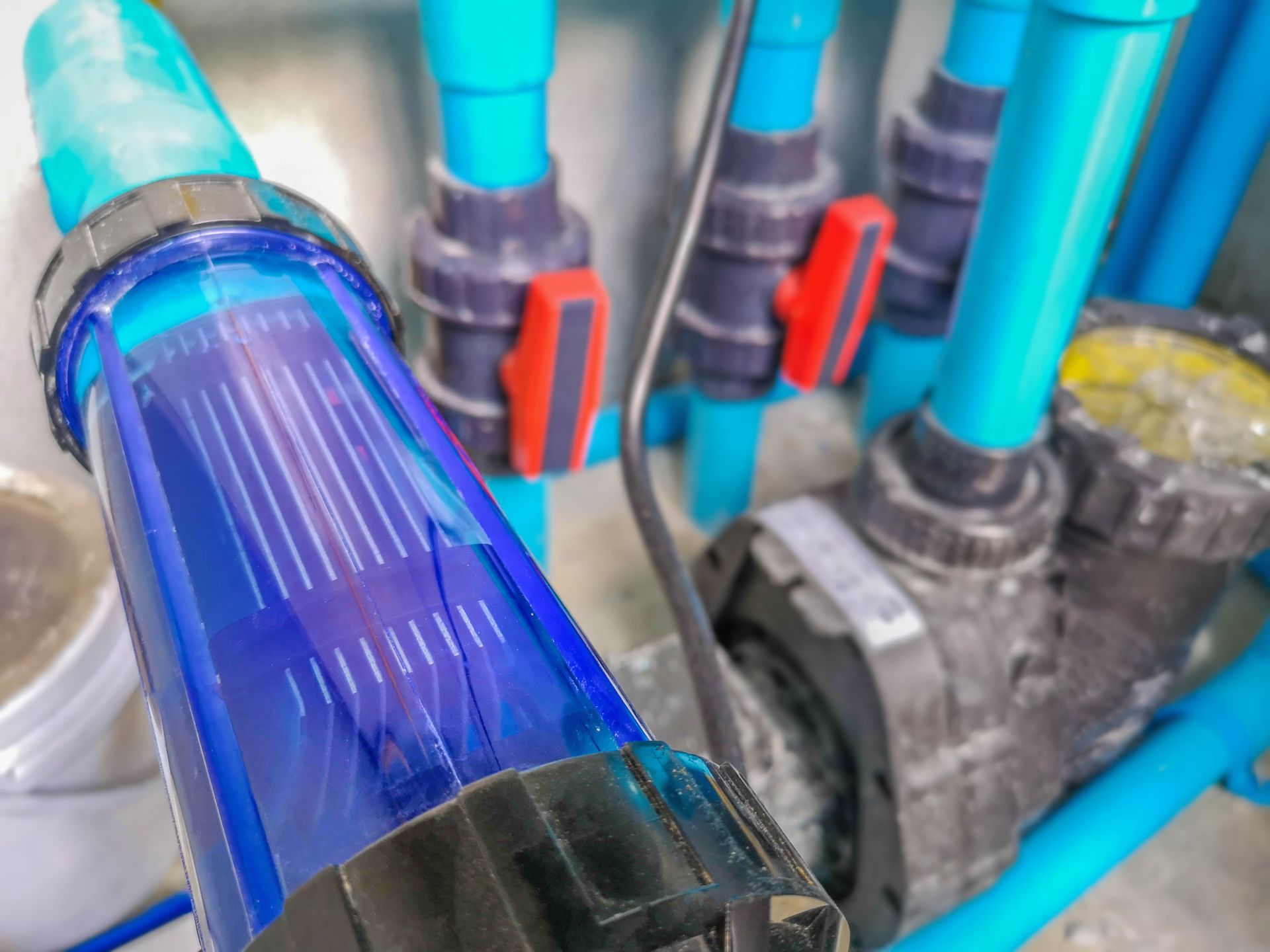 Blue and black plumbing pipes with red valve handles in a utility area