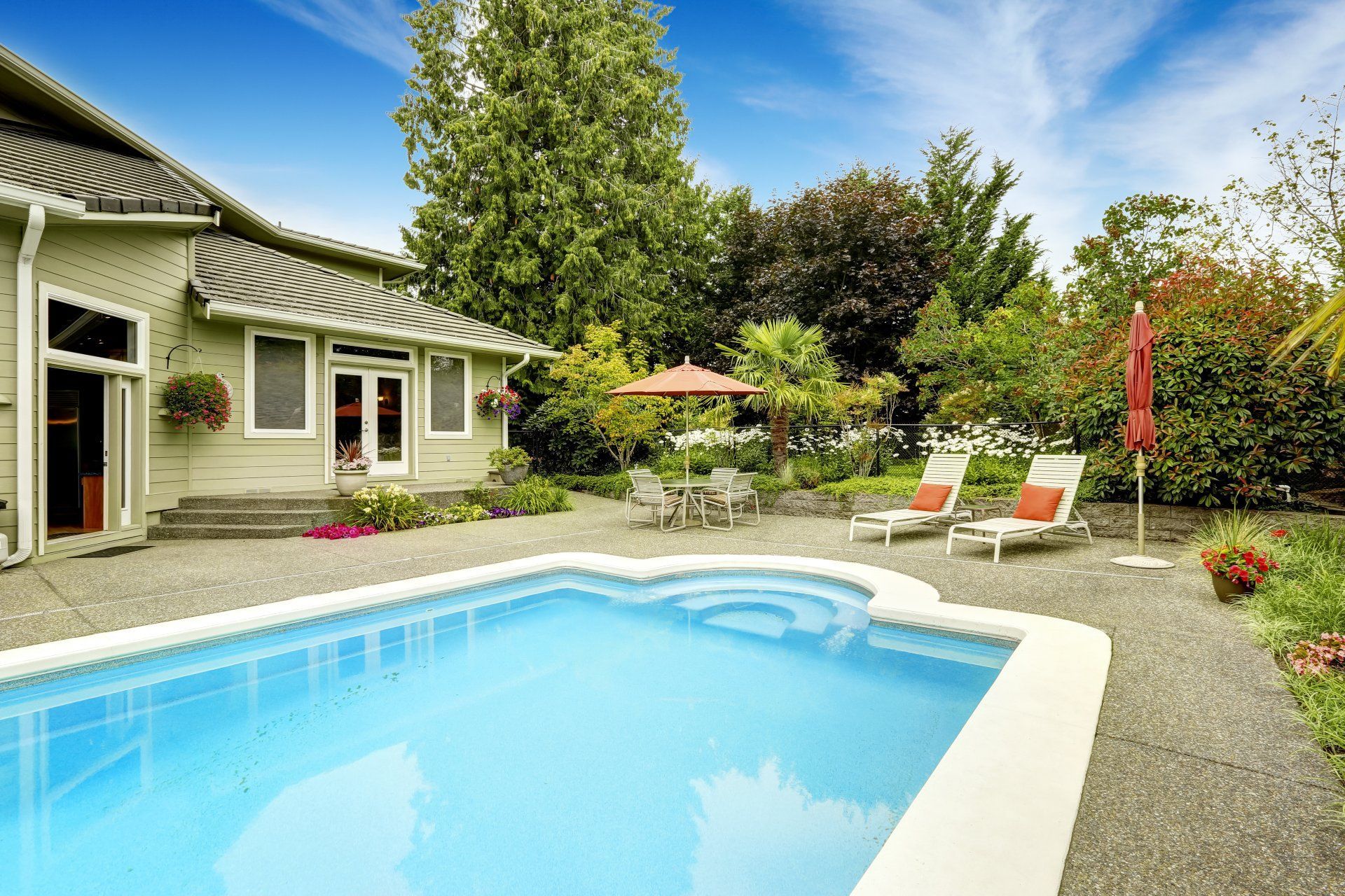 There is a large swimming pool in the backyard of a house.