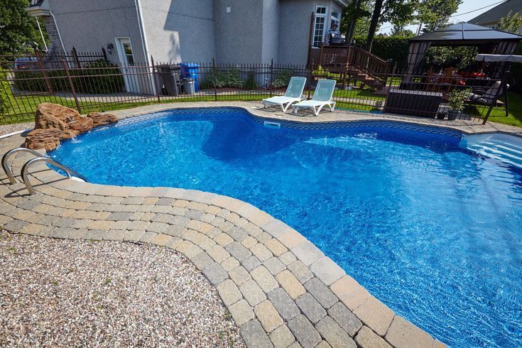A large swimming pool with a brick walkway surrounding it