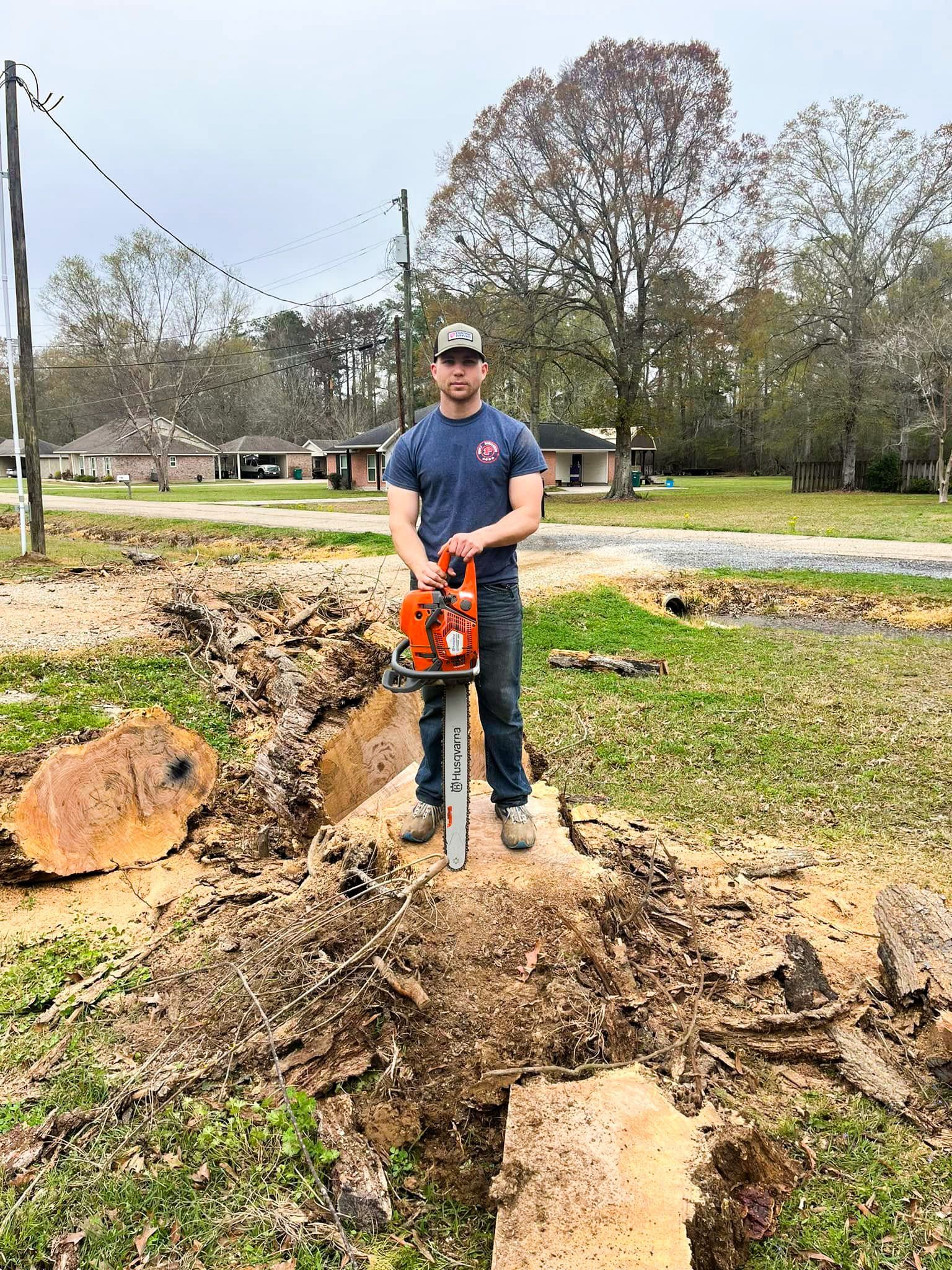 A man is standing next to a tree stump holding a chainsaw.