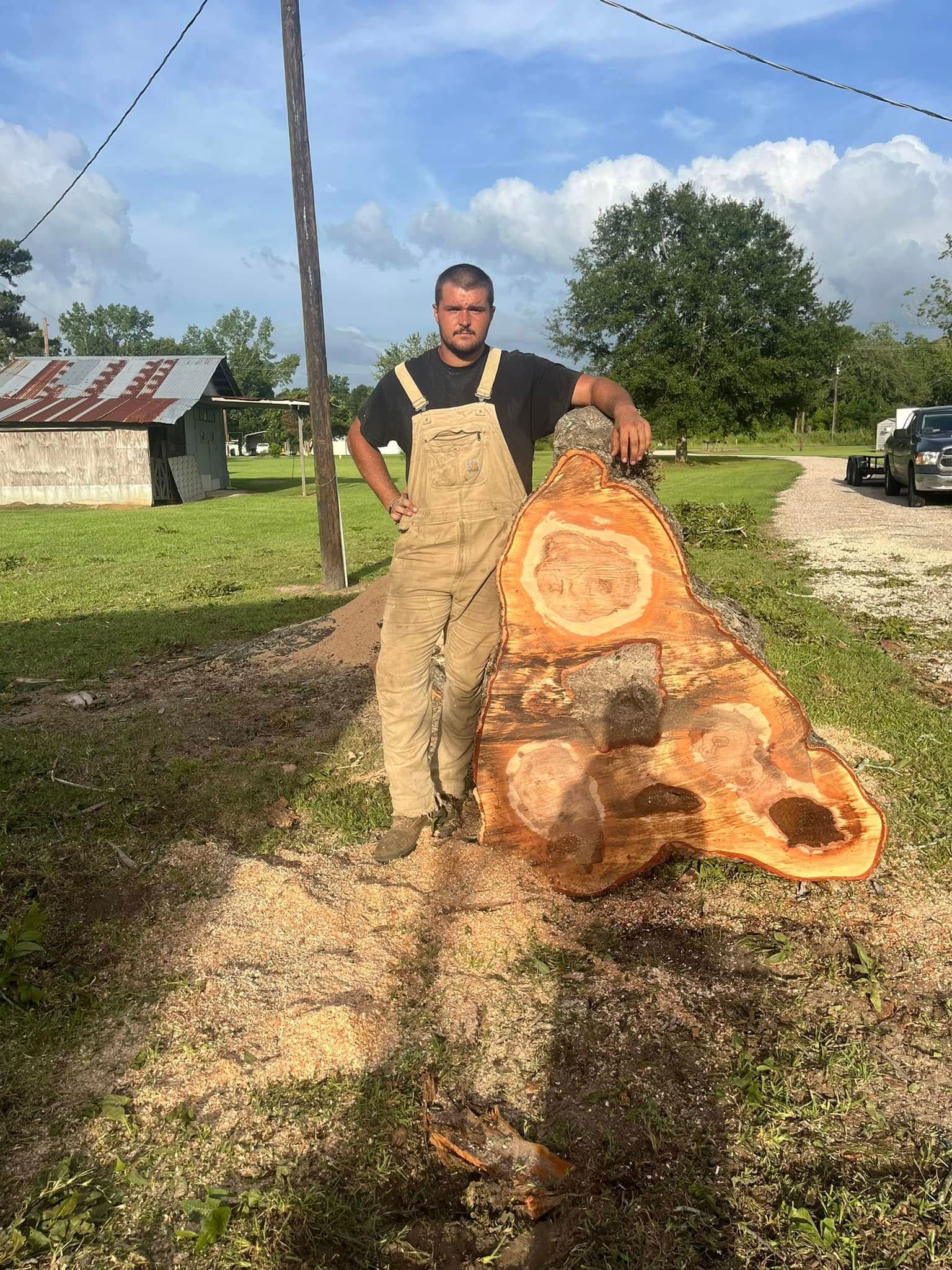 A man is standing next to a large piece of wood.