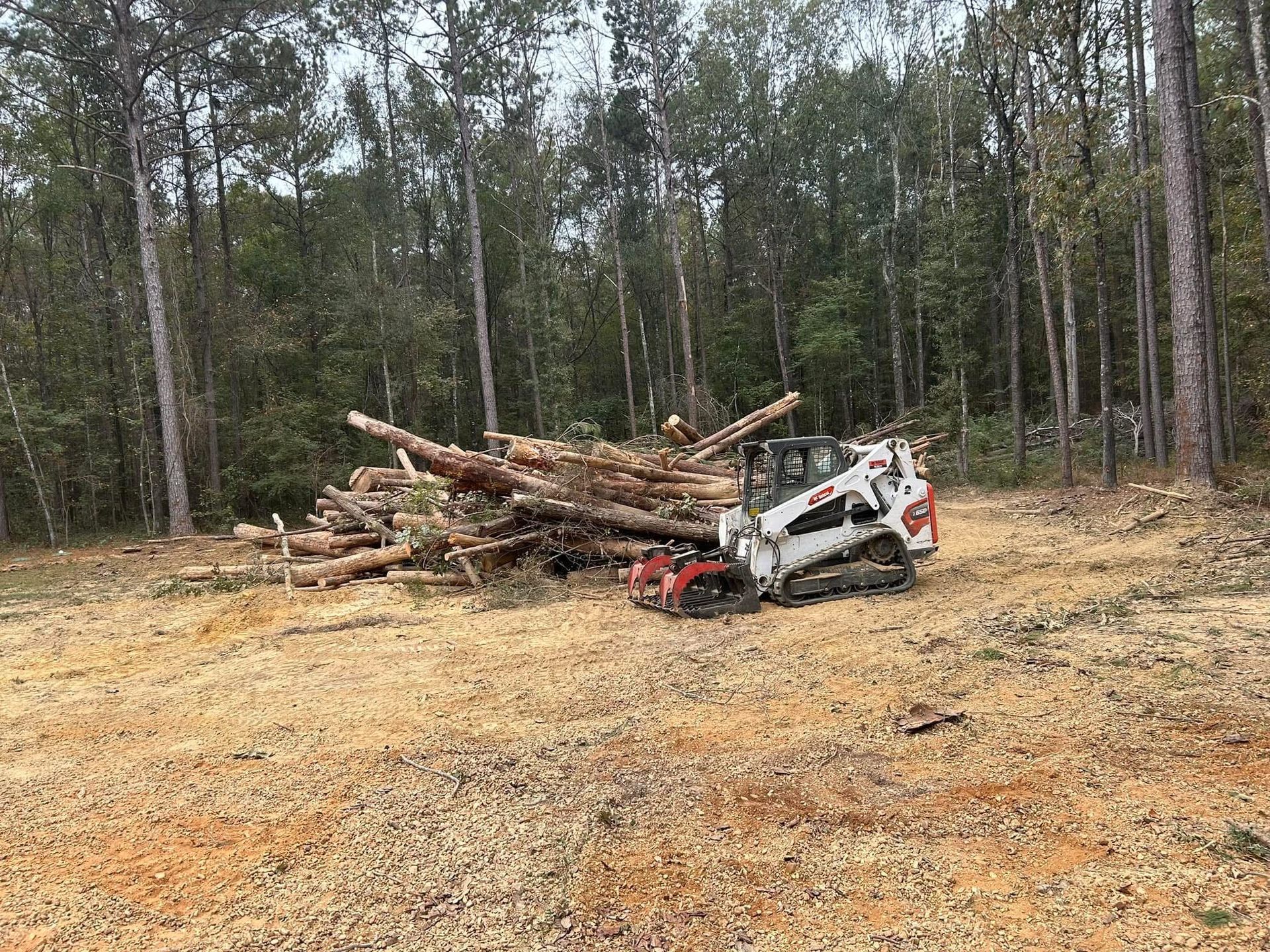 A bulldozer is sitting in a field next to a pile of logs.