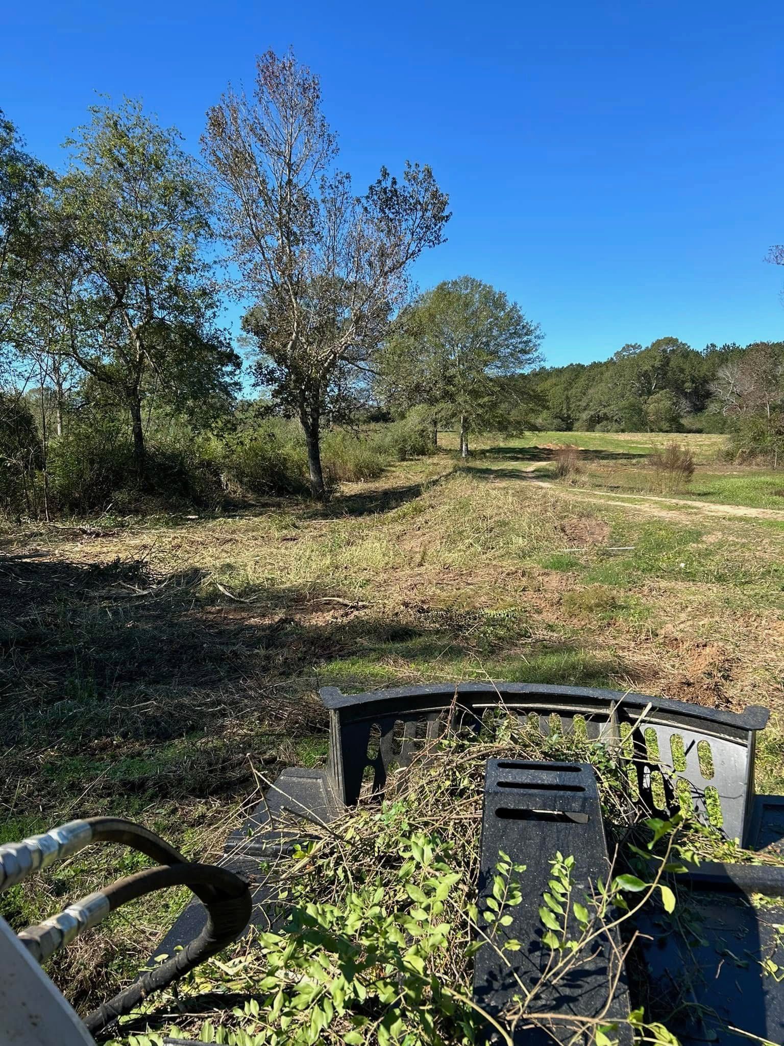 A tractor is sitting in the middle of a field with trees in the background.