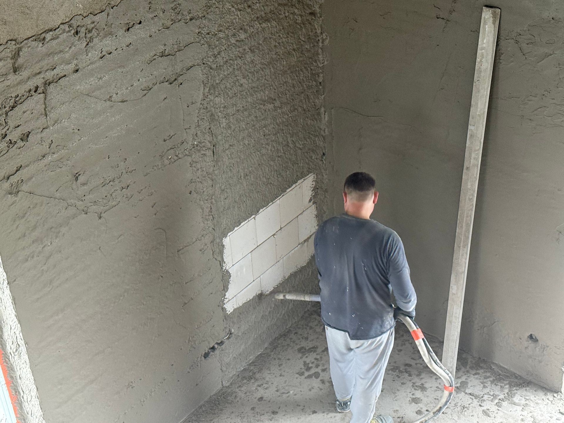 Vyras purškia sienas tinku
