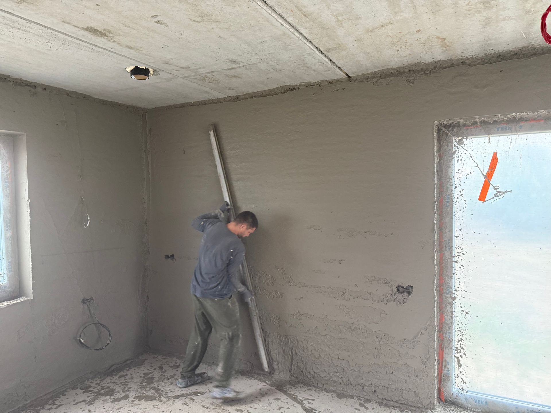 Vyras kambaryje lygina sieną gulsčiuku.