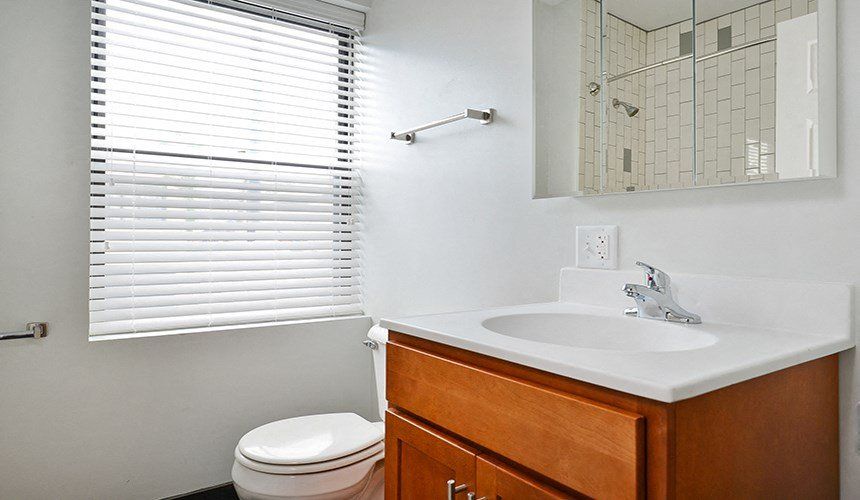 A bathroom with a toilet , sink , mirror and window at 1640 N Damen Apartments.