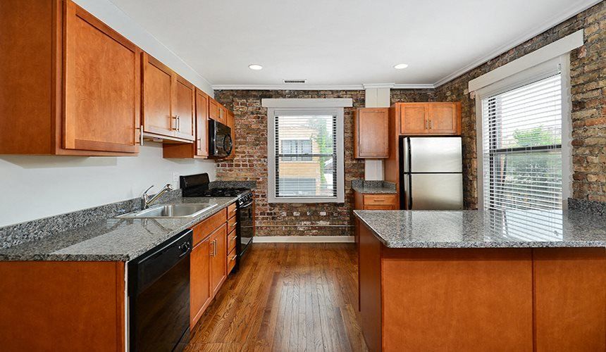 A kitchen with wooden cabinets , granite counter tops , stainless steel appliances and a window at 1640 N Damen Apartments.