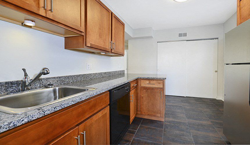 A kitchen with a sink , dishwasher , refrigerator and wooden cabinets at 1640 N Damen Apartments.