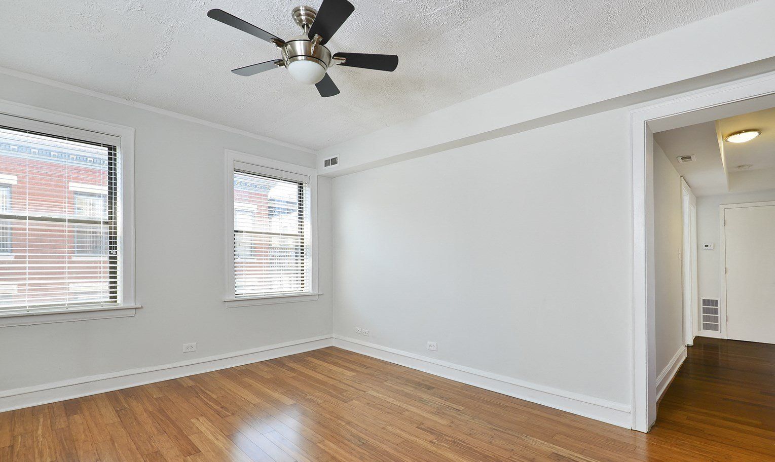 An empty room with hardwood floors and a ceiling fan at 1640 N Damen Apartments.