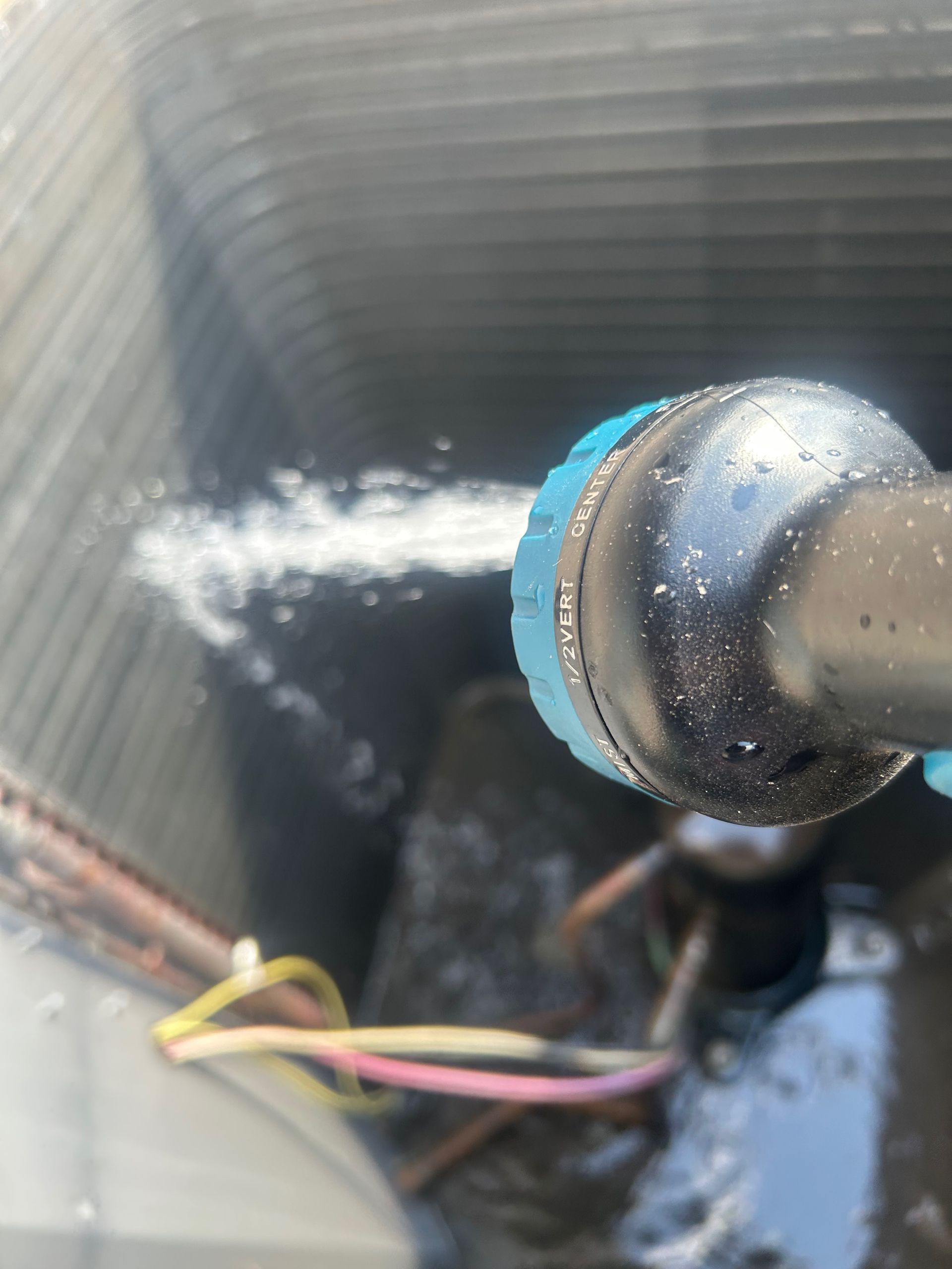 A person sprays water into an air conditioner's cooling fins.