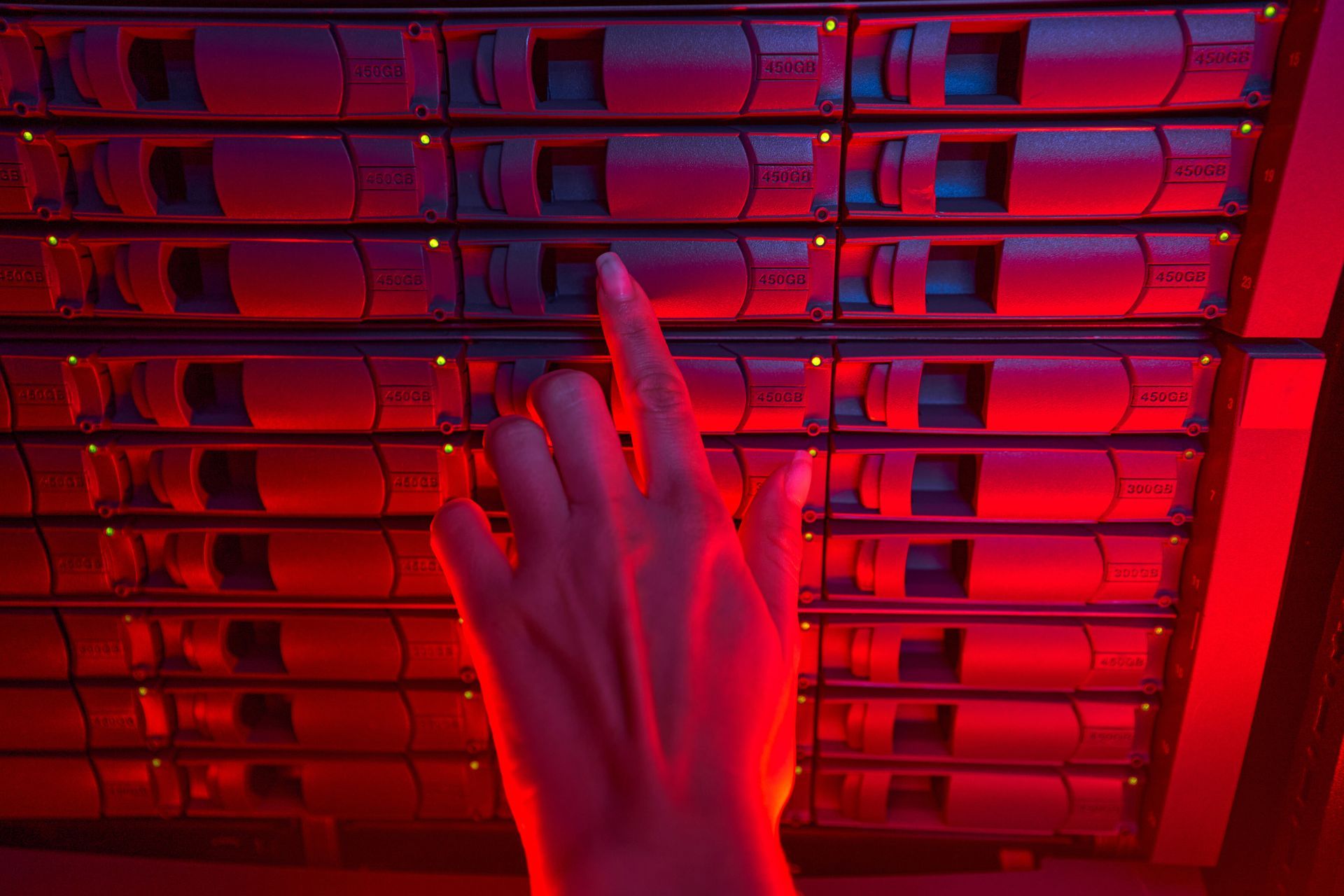 Een persoon raakt een rode server aan in een datacenter.