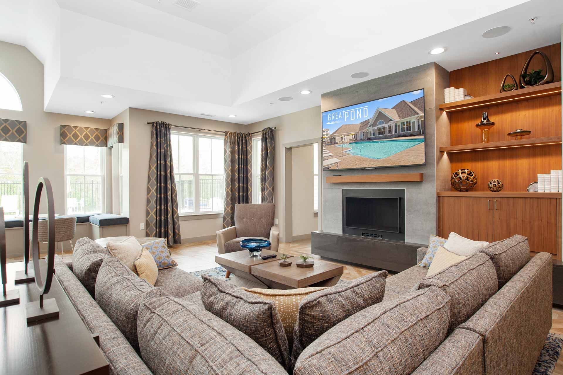 The Residences at Great Pond apartment with fire place, TV, sofa, and windows. 