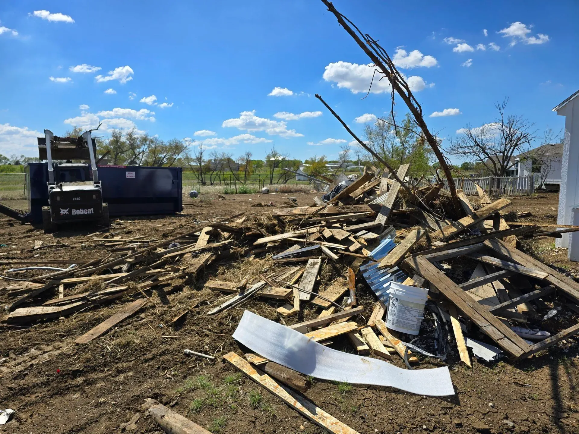 A pile of wood is laying on the ground in a field.