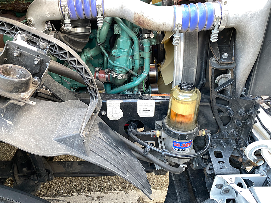 A close up of a car engine with a fuel filter attached to it.