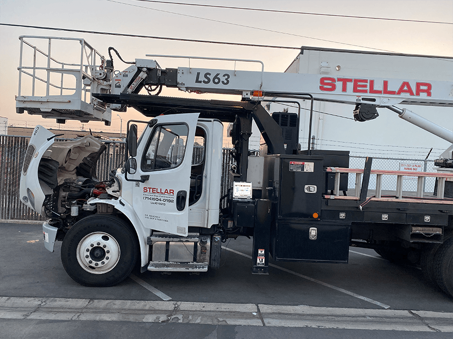 A white truck with a crane on top of it is parked in a parking lot.