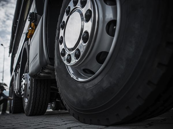 A close up of a truck 's tire on a brick road.