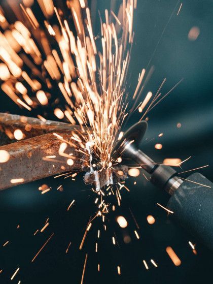 a person is grinding a piece of metal with sparks coming out of it .