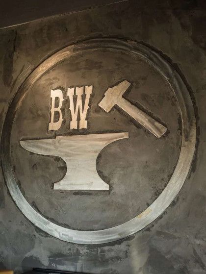 a logo for a blacksmith shop with an anvil and hammer .