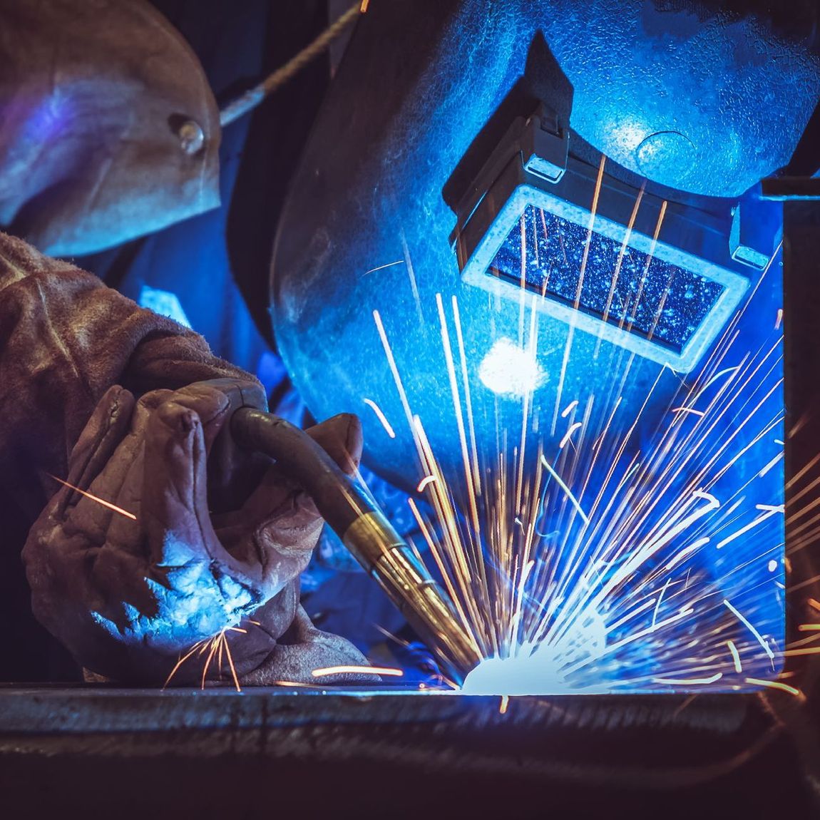 a man wearing a welding mask is welding a piece of metal