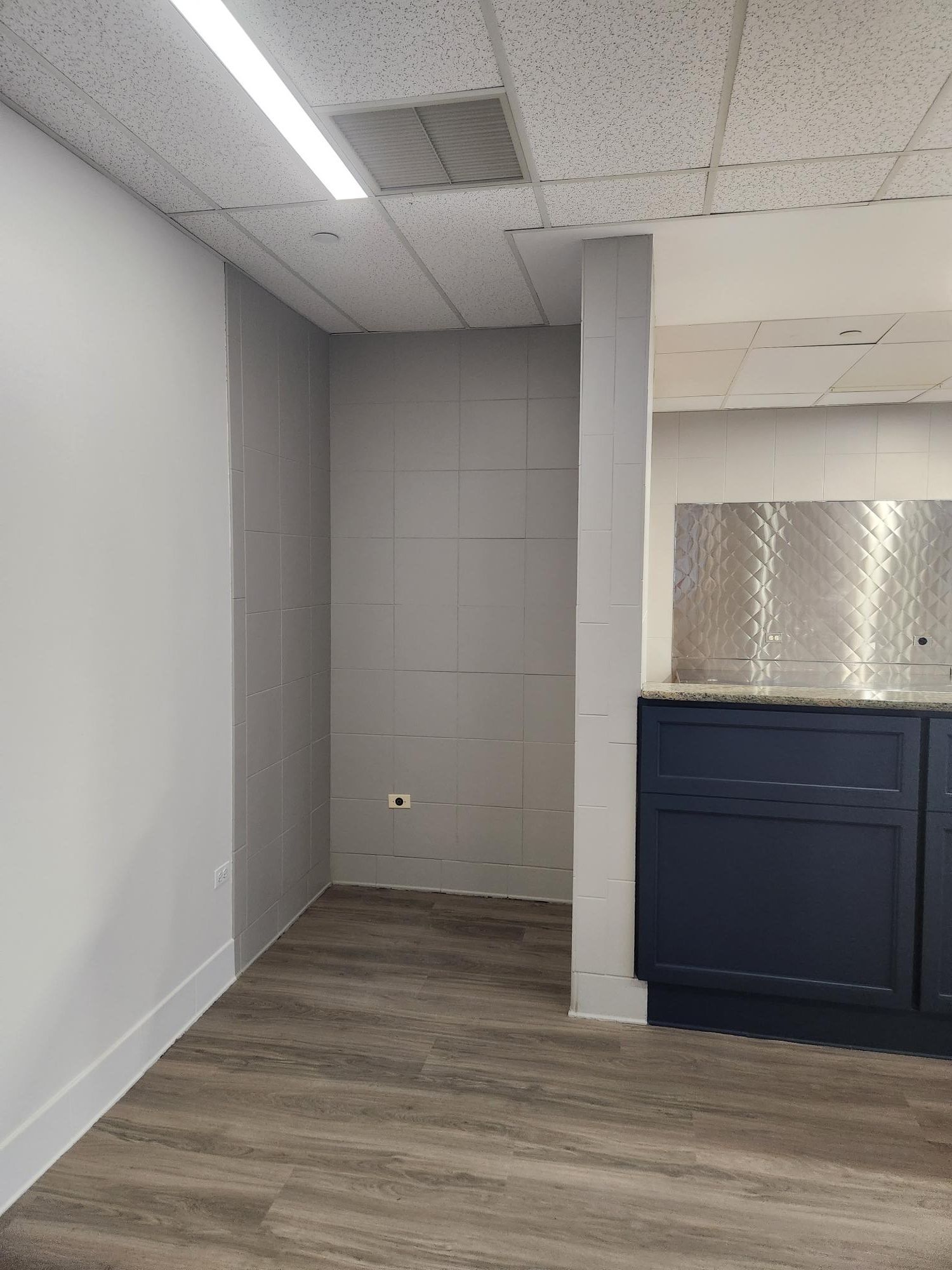 An empty room with a wooden floor and a stainless steel counter top.