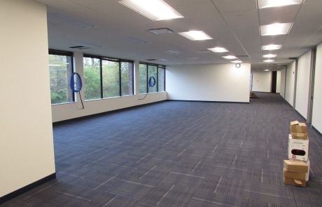 A large empty room with a lot of windows and boxes on the floor