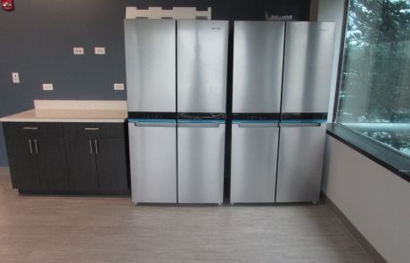Three stainless steel refrigerators are lined up in a kitchen