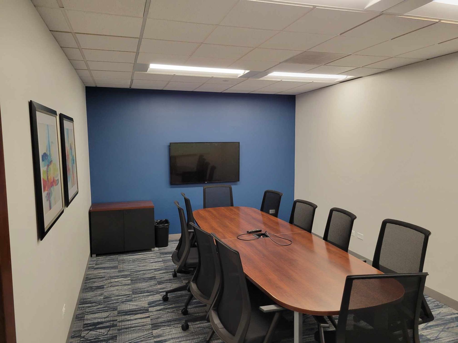 A conference room with a long table and chairs and a flat screen tv.