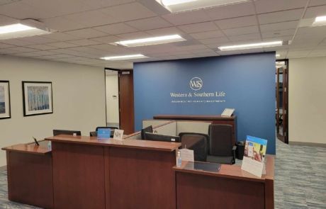 A reception area in an office with a blue wall and a wooden desk.